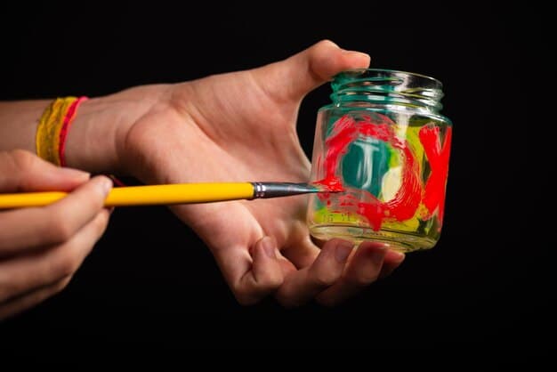A close-up shot of hands carefully painting intricate floral designs on a repurposed glass jar, surrounded by various eco-friendly craft supplies like natural paints and brushes.