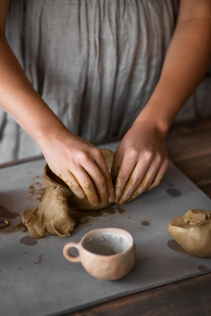 A serene setting with hands gently shaping clay into a small decorative bowl, surrounded by natural light, calming colors, and a few essential crafting tools, evoking a sense of peaceful concentration.