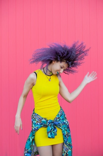 A vibrant, maximalist fashion scene with a model wearing a combination of brightly colored patterns, textures like sequins and faux fur, and oversized statement jewelry. The background is a lively street art mural, enhancing the visual explosion of colors and creativity.