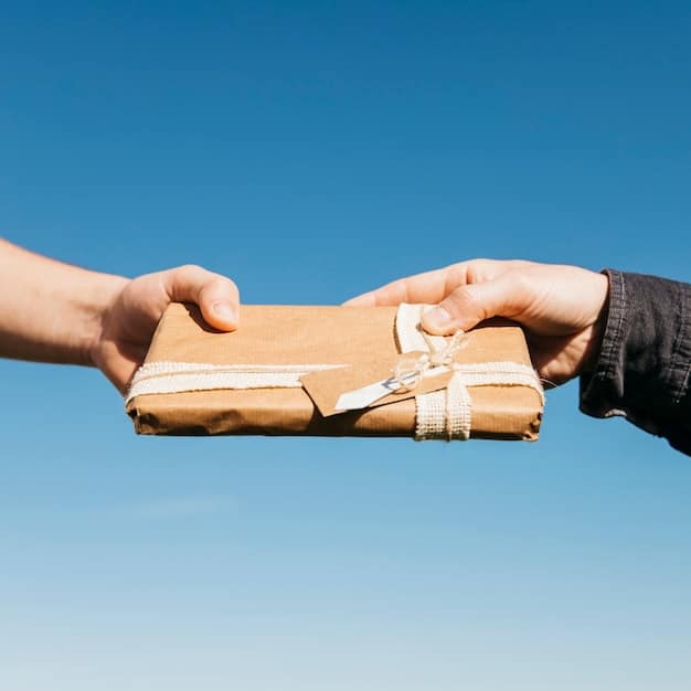 A person's hands holding a package with a return label clearly visible, standing near a postal service drop-off point.