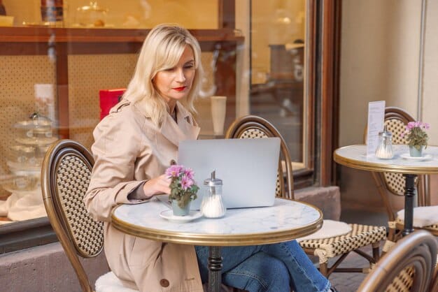 A fashion influencer is shown sitting at a cafe, using her laptop to plan her content calendar. The screen displays a project management platform with various tasks organized by category and priority. Notes, deadlines, and collaboration details are clearly visible, emphasizing the importance of digital tools for Fashion Influencer Time Management: Balancing Content Creation and Personal Life in 2025.