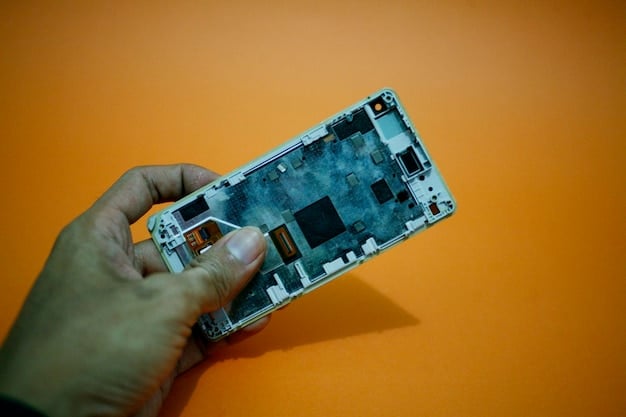 A close-up shot of a disassembled smartphone, revealing low-quality internal components and cheap wiring. The image emphasizes the potential hidden compromises in the quality of electronics purchased from Temu, directly relating to the theme of Is the Temu Electronics Haul Too Good to Be True? A 2025 Investigation.