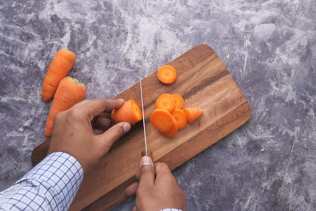 A person struggling to slice a carrot using a vegetable slicer, with uneven and broken slices scattered around. The image illustrates the difficulty of using the gadget with harder vegetables, highlighting a common issue found during 