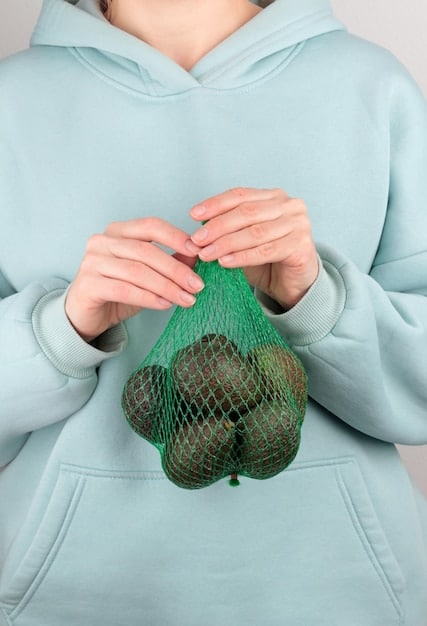 A close-up of hands holding a piece of fabric made from recycled plastic bottles. The fabric is colorful and textured, highlighting the innovative use of waste materials in fashion. This helps us ask: Is the recycled material as acceptable as a new one?