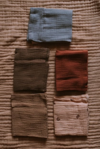 A close-up shot showcasing fabric swatches in earthy tones like terracotta, olive green, and rust. The textures of the fabrics (wool, cotton, and knit) are visible, creating a tactile and inviting visual. The lighting emphasizes the warmth and depth of the colors, reflecting a cozy and natural aesthetic, and hinting at what are the top 5 trending colors for fall 2025, according to Pantone?.